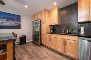 A modern kitchen with wooden cabinets, stainless steel appliances, and a marble countertop.