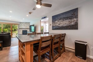 A modern kitchen with a dining area, a fireplace, and a large painting on the wall.