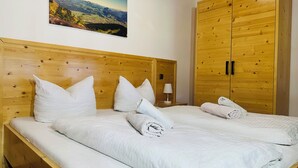 Un letto matrimoniale con biancheria e cuscini bianchi, una testiera in legno e un armadio in legno con due ante.