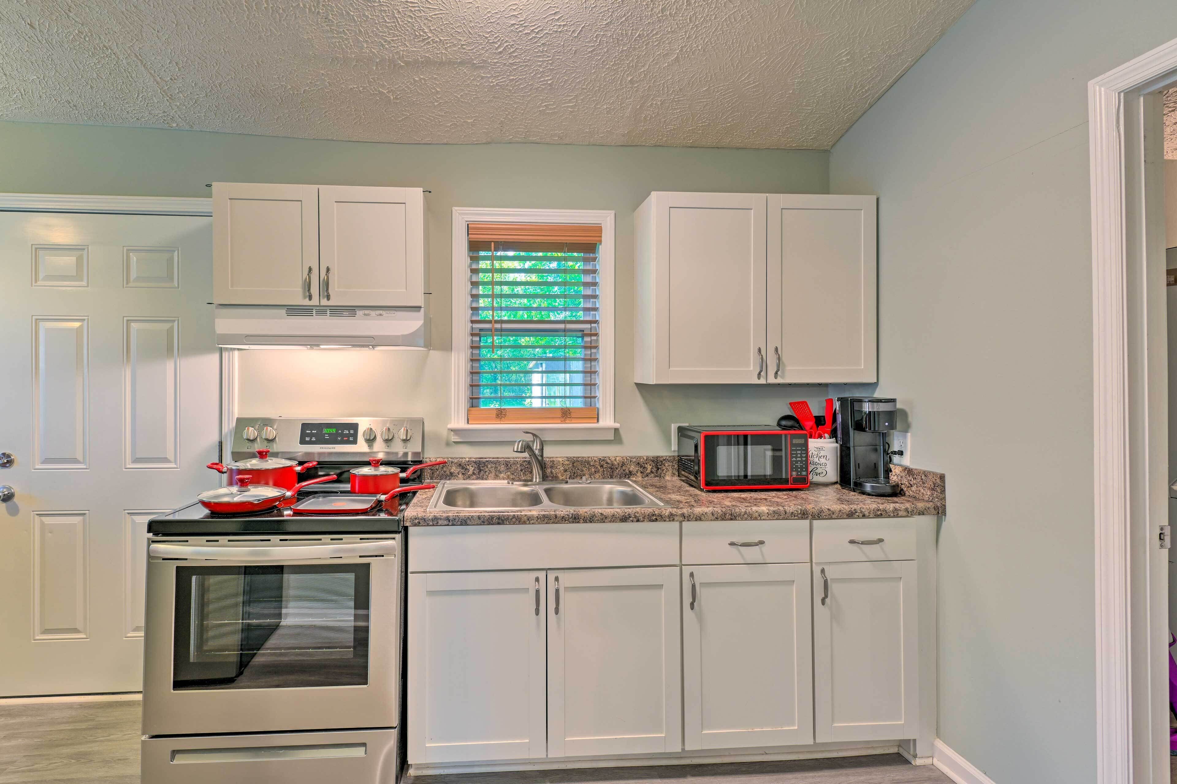 A kitchen with white cabinets, a stainless steel stove, a microwave, and a sink.