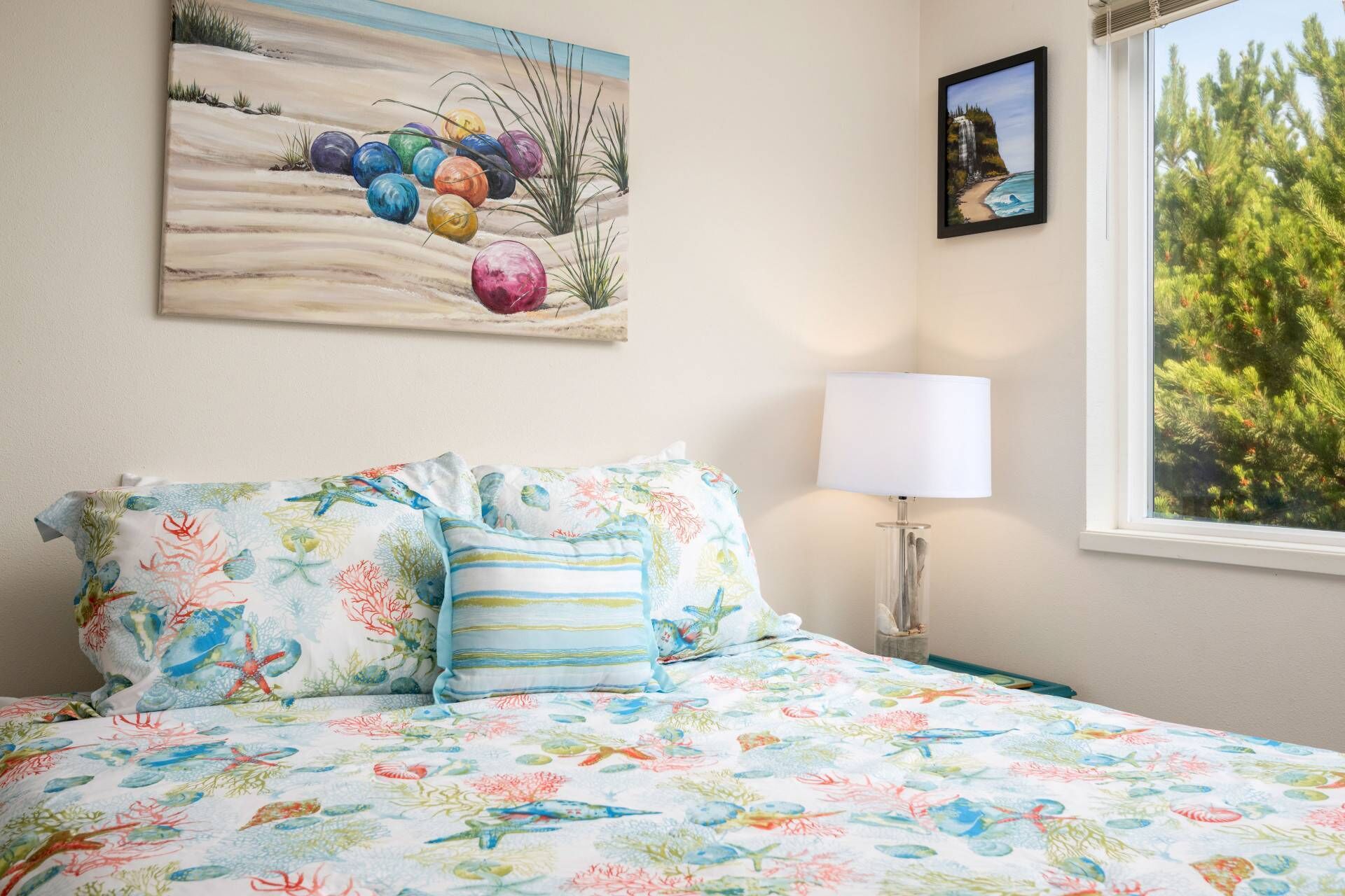 A bedroom with a bed, a painting, a window, and a lamp.