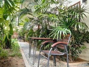 Un banc et une table dans un espace jardin agrémenté de diverses plantes et doté d’un chemin de gravier.