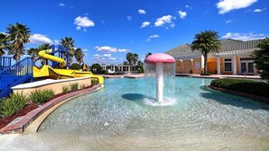 Um parque aquático com uma piscina transparente, um escorregador amarelo e um atrativo aquático rosa.