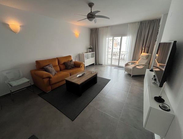 Een moderne woonkamer met een bank, salontafel en televisie.