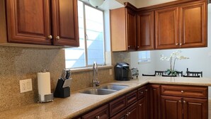 A kitchen with granite countertops, wooden cabinets, a stainless steel sink, and a window with a view.