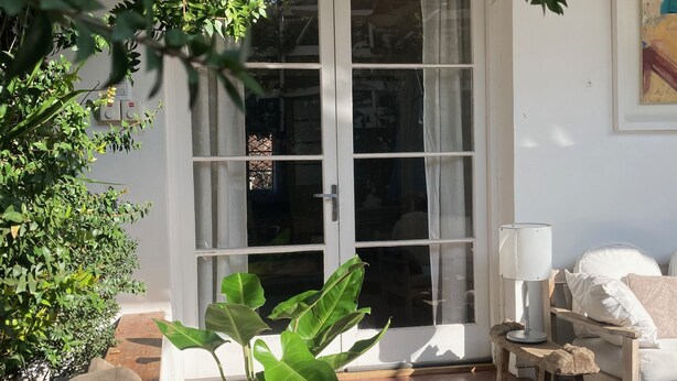A patio area with a white sofa, a wooden table, and a potted plant.