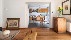 A modern living room with a glass coffee table, a sofa, and a wooden cabinet. A framed picture hangs on the wall.