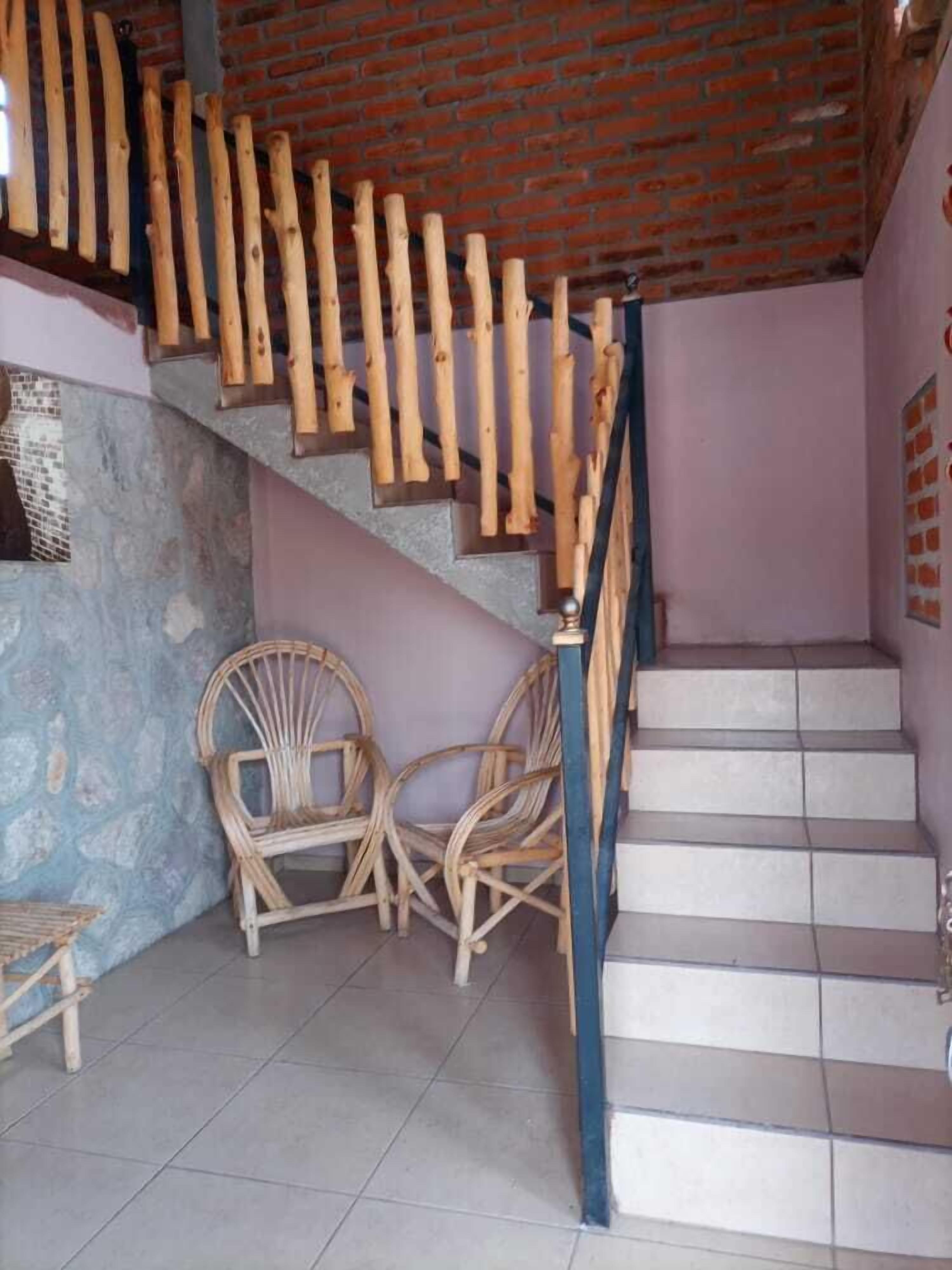 Una escalera con barandillas de madera, una silla y suelo de baldosas.