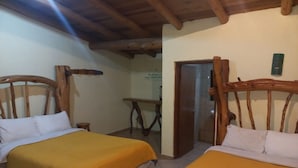 A room with two wooden beds with yellow bedding, a wooden ceiling, and a small table with a chair. - Posada Margarito (Urique)