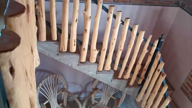 A staircase with wooden handrails and a brick wall in the background. - Posada Margarito (Urique)