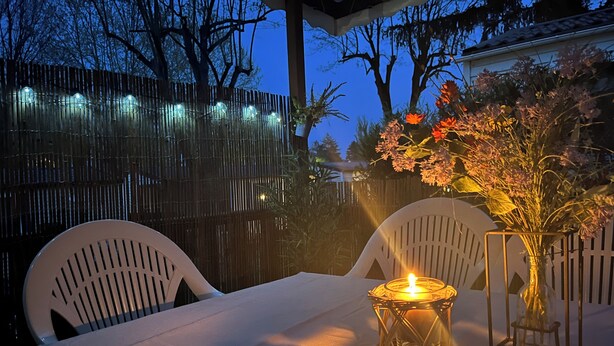 A table set outdoors with a candle, chairs, and a vase of flowers. - Mobile Home Dans Camping Calme (Biesheim)