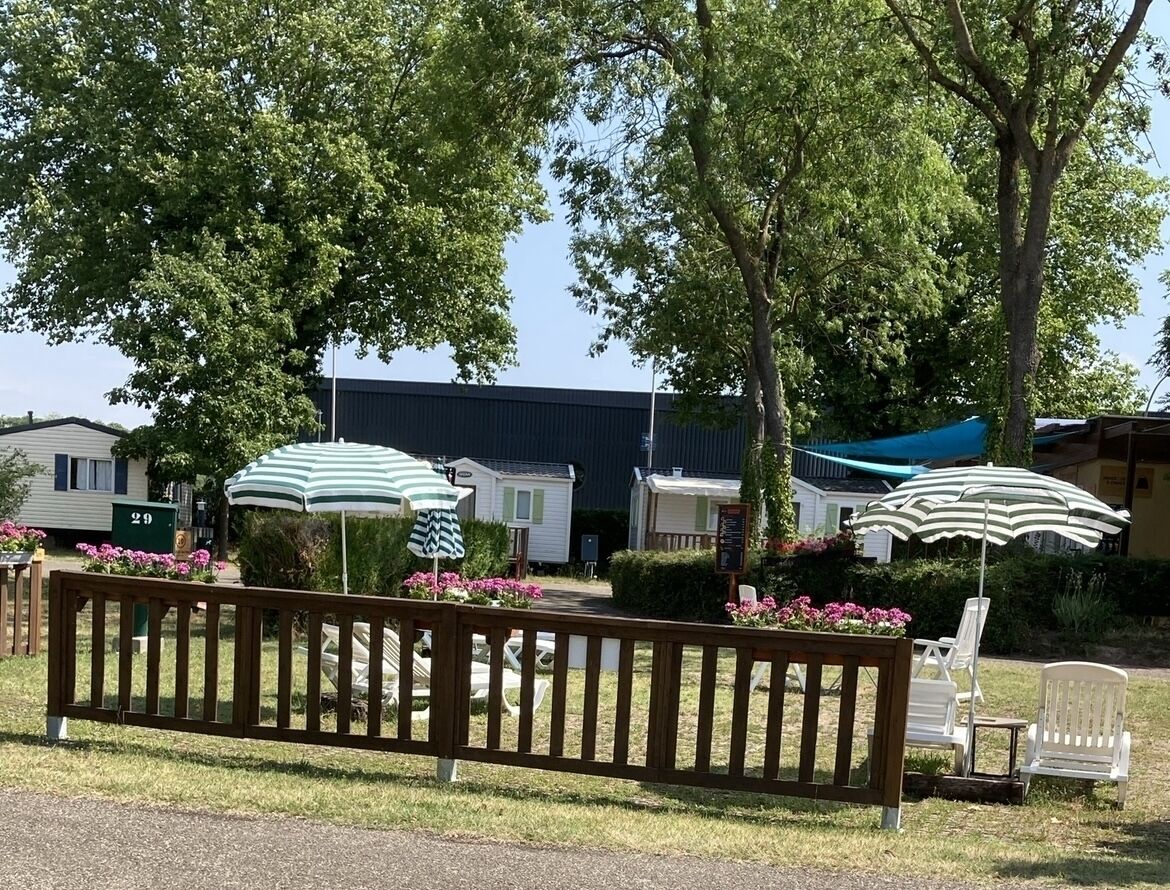 Eine Reihe von Mobilheimen mit Außenbereichen zum Sitzen, jedes mit einem gestreiften Sonnenschirm.