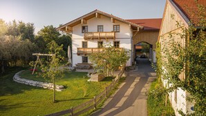 Ein zweistöckiges Haus mit einem Balkon, ein Garten mit Schaukel und ein gepflasterter Auffahrt.