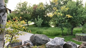 Ein angelegter Garten mit großen Steinen, einem Pfad und einem Teich, der von Bäumen umgeben ist.