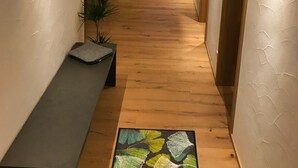 Ein schmaler Korridor mit Holzboden, einer Bank und einem gemusterten Teppich.