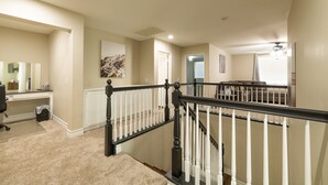 A spacious living area with a staircase, a large mirror, and a painting on the wall.