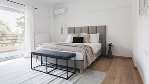 A modern bedroom with a bed, bench, and bedside table. - Stellar 3BR Apartment with Balcony (Paleo Faliro)
