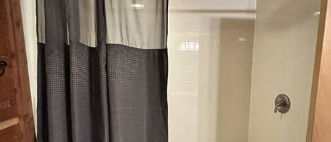 A bathroom with a shower curtain, a bathtub, and a glass-enclosed shower area.