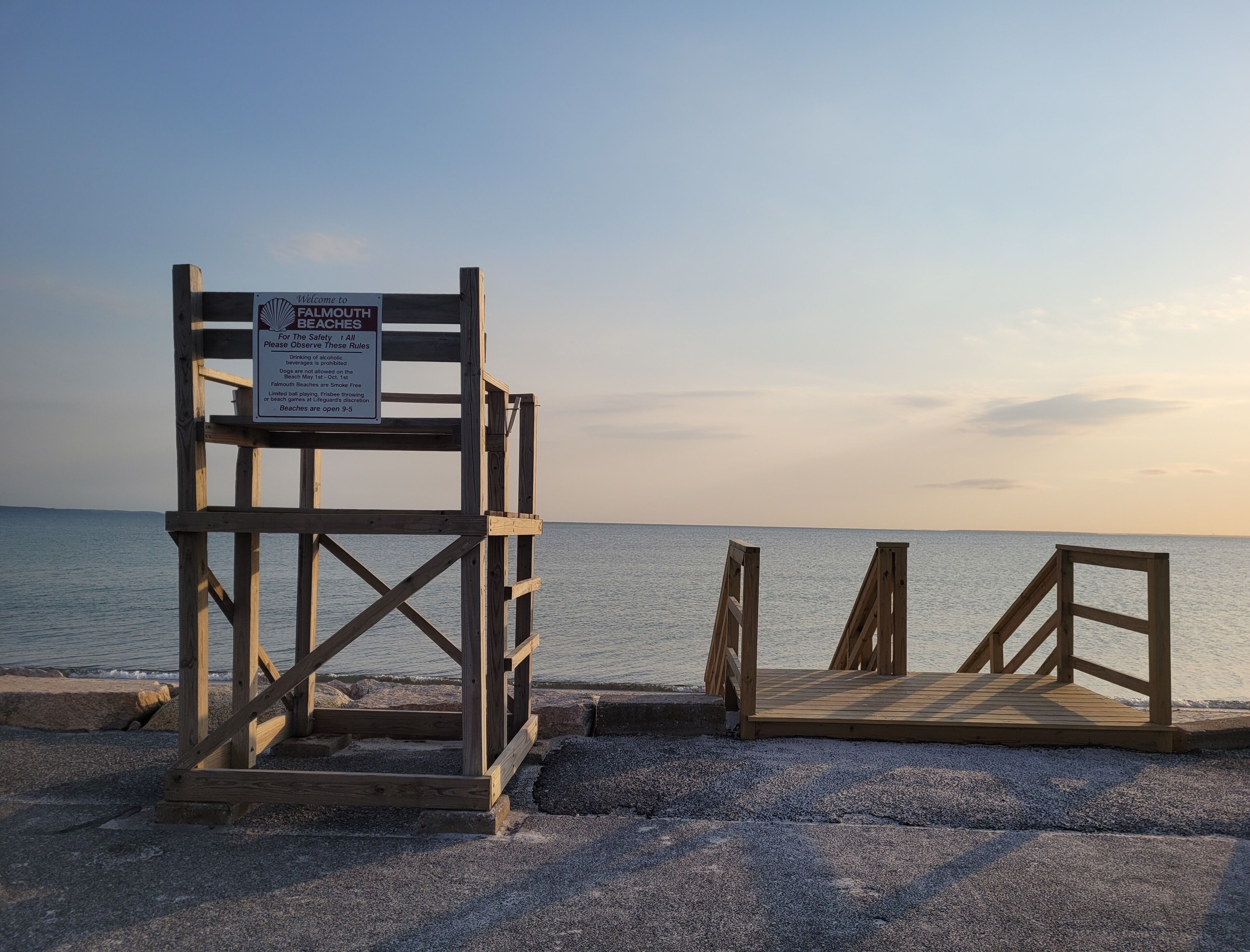 Une chaise de plage en bois et un panneau indiquant les règles de sécurité sur une plage.
