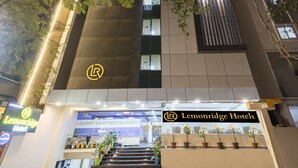 Un hôtel avec une enseigne indiquant « Lemonridge Hotels » et un restaurant appelé « Curry Leaf Restaurant ».