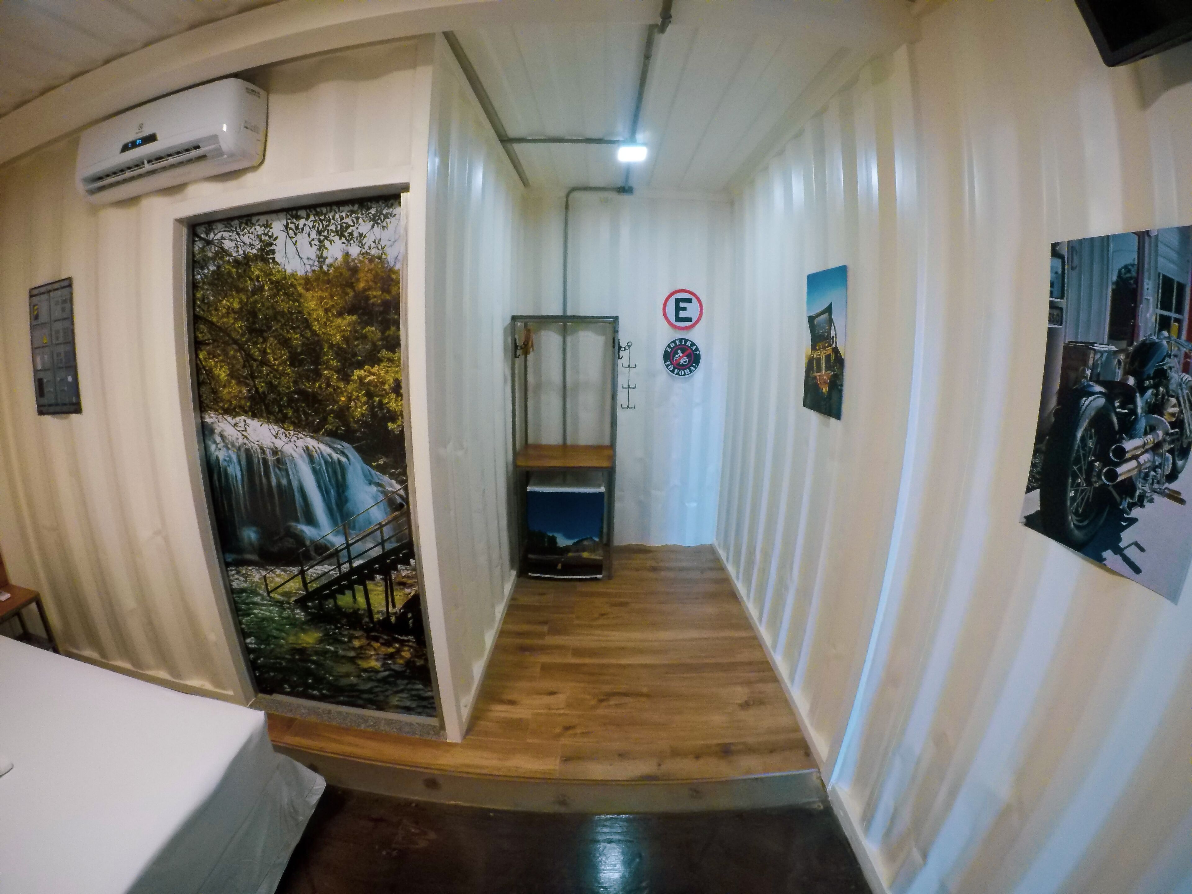 Um corredor com um mural de uma cascata, um aviso de proibição de fumar e um cartaz de uma motocicleta.