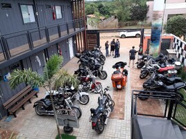 Un patio con varias motocicletas estacionadas, un banco y un edificio con balcones.