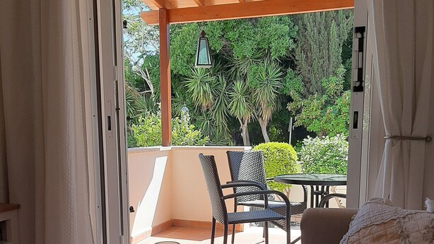 A room with a wooden ceiling, a sofa, a table with two candles, and a view of greenery outside. - Luxury Maisonette 250m from the beach. (Kato Paphos)