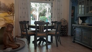 A dining area with a table and chairs, a chandelier, a cabinet, and a painting on the wall. - Luxury Maisonette 250m from the beach. (Kato Paphos)