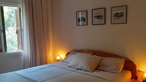 A bedroom with a bed, curtains, a window, and wall-mounted pictures. - Luxury Maisonette 250m from the beach. (Kato Paphos)