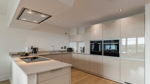 Eine moderne Küche mit einer zentralen Kochinsel, eingebauten Backöfen und einem eleganten Design.