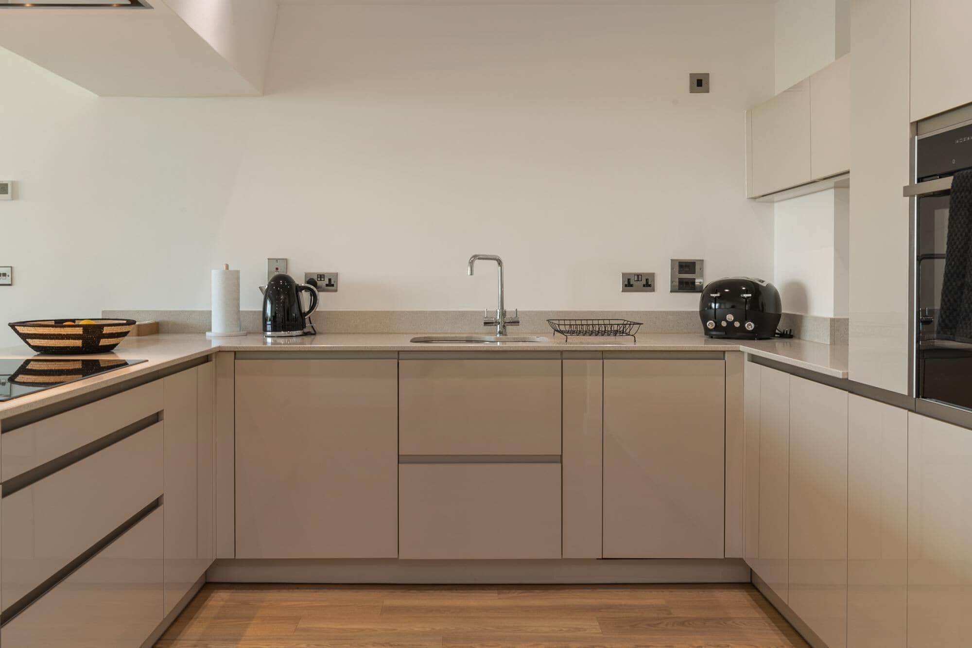 Una cocina moderna con pileta integrada, hervidor de agua, tostadora y panera.