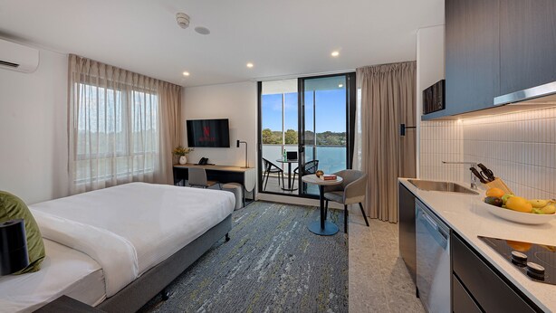 Una habitación de hotel con cama, escritorio, silla y kitchenette.