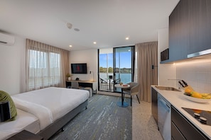 A hotel room with a bed, desk, chair, and kitchenette. - Littomore Suites Kingswood (Kingswood)