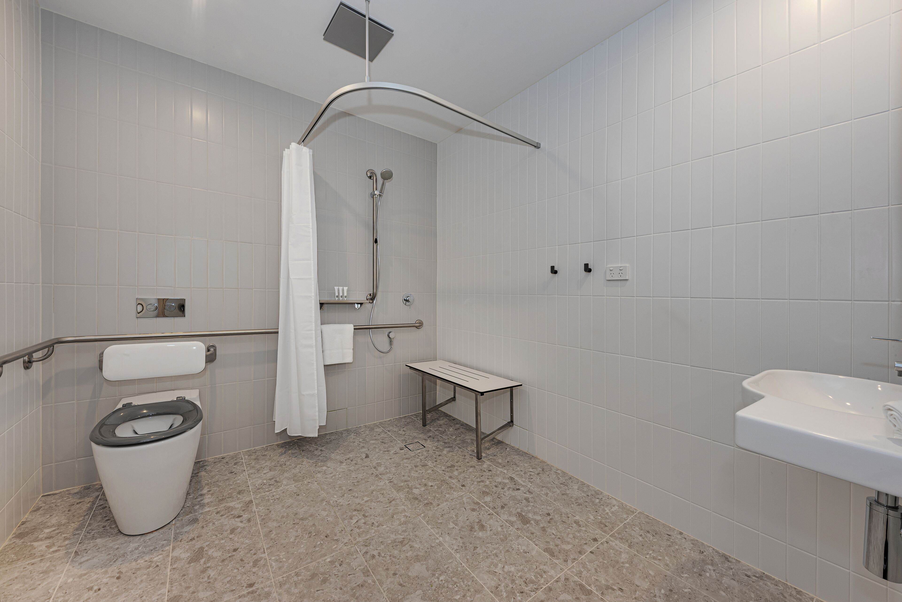 A modern bathroom with a toilet, shower, and sink.