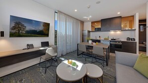 Una habitación de hotel moderna con comedor, kitchenette y un gran ventanal con cortinas.