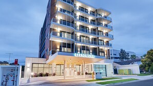 Un hotel moderno con varios balcones, una entrada bien iluminada y vistas claras del entorno.