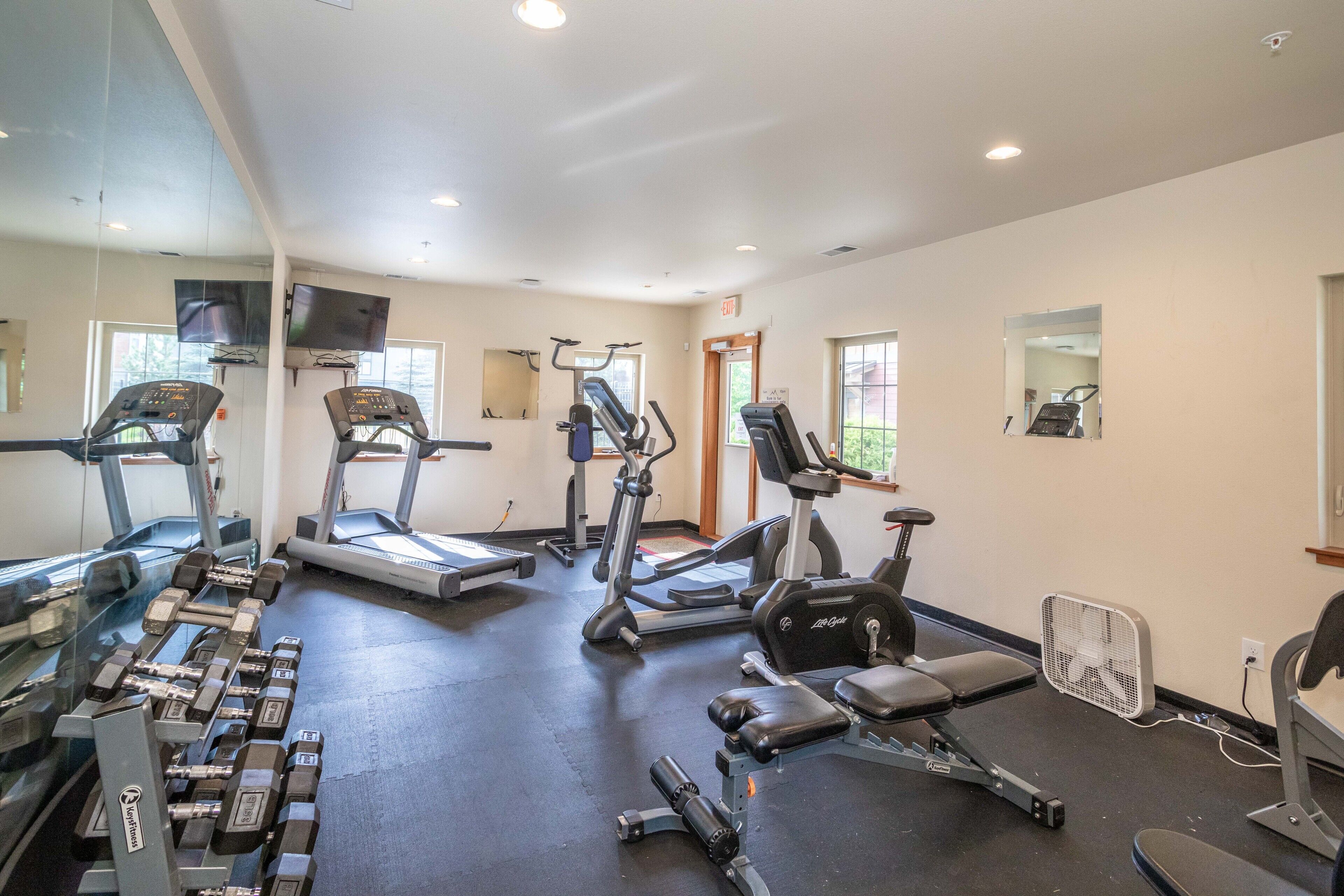 Une salle de sport équipée de tapis de course, de vélos elliptiques et de poids libres.