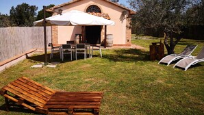 Un petit patio extérieur avec une table et des chaises, un banc en bois et un espace salon abrité.
