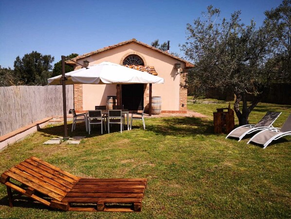 A small outdoor patio with a table and chairs, a wooden bench, and a covered seating area. - Dependance surrounded by greenery (Toscana)