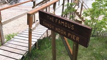 A wooden sign with the text "The Famous Sandy Hook Pier" at a beachside location.