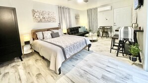 Una habitación de hotel moderna con una cama grande, un sofá, una mesa de comedor y un ventilador de techo.