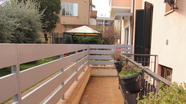 A narrow outdoor corridor with a brick floor, metal railings, and potted plants. - A home as comfortable as yours, but with the novelty you've been looking for!  (Foligno)