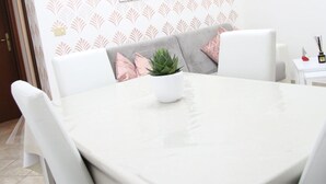 A dining area with a round table, white chairs, a grey sofa with pink cushions, a potted plant, and a small white table with a Buddha statue and incense sticks. - A home as comfortable as yours, but with the novelty you've been looking for!  (Foligno)