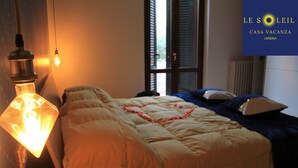A bedroom with a bed, a wall-mounted light fixture, and a window with shutters. - A home as comfortable as yours, but with the novelty you've been looking for!  (Foligno)
