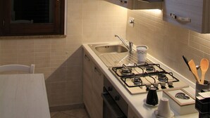 A modern kitchen with a gas stove, sink, and hanging light fixture. - A home as comfortable as yours, but with the novelty you've been looking for!  (Foligno)