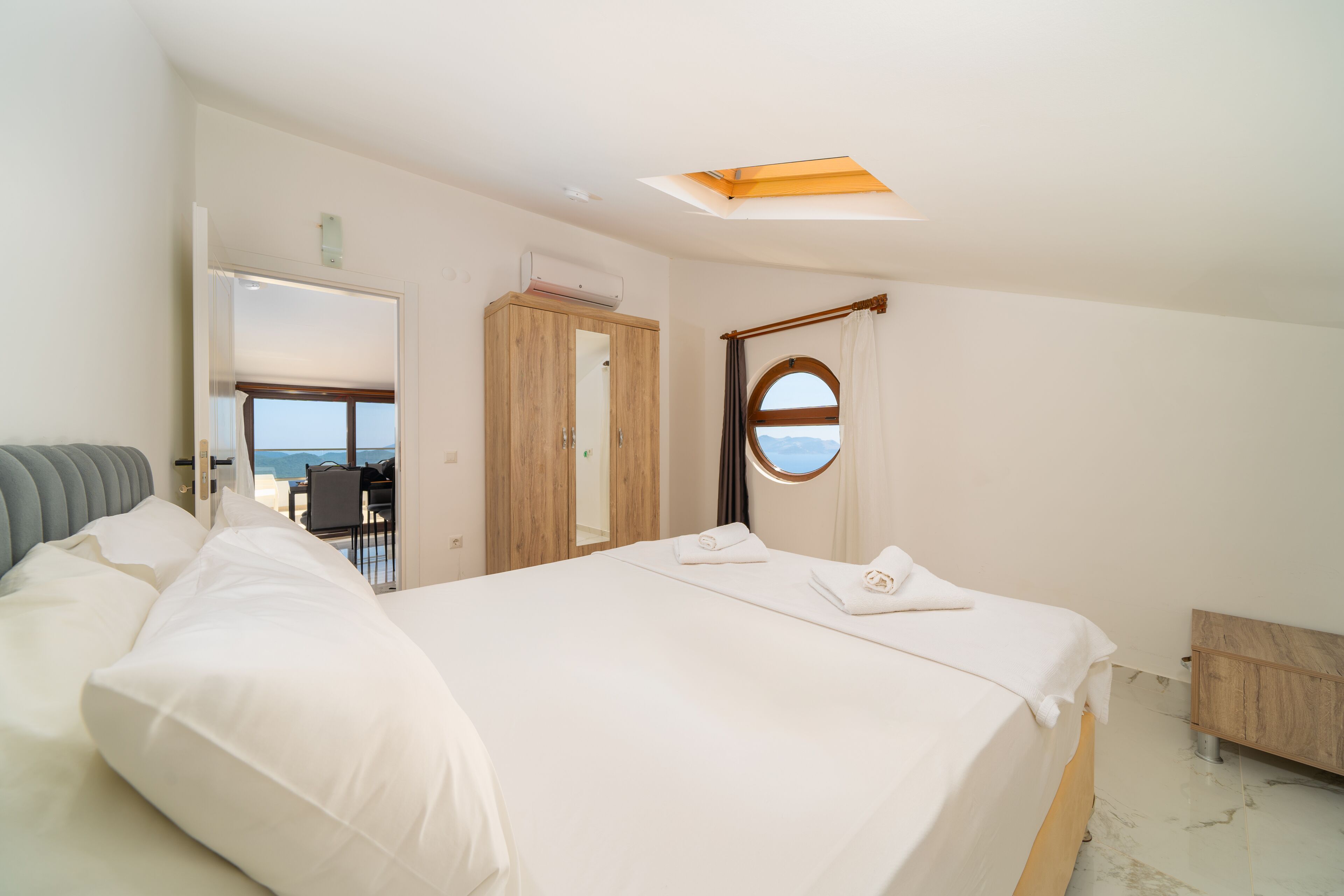Una camera da letto moderna con un letto grande, un lucernario, vista dal finestrino e un'armadio in legno.