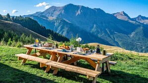 Ein Picknicktisch auf einer grasbewachsenen Hügelkuppe mit Blick auf einen Berg im Hintergrund.