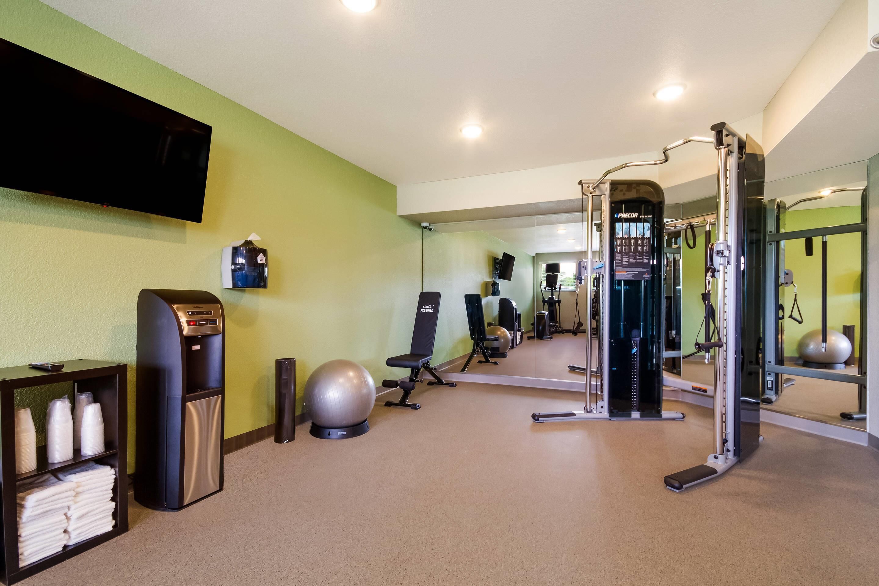 A gym with exercise equipment, a water dispenser, and a mirror.
