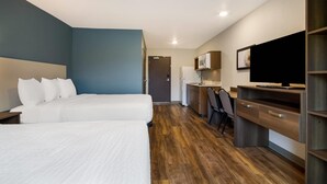 A hotel room with two beds, a desk, a chair, a TV, and a microwave. - Woodspring Suites Panama City Beach (Panama City Beach)