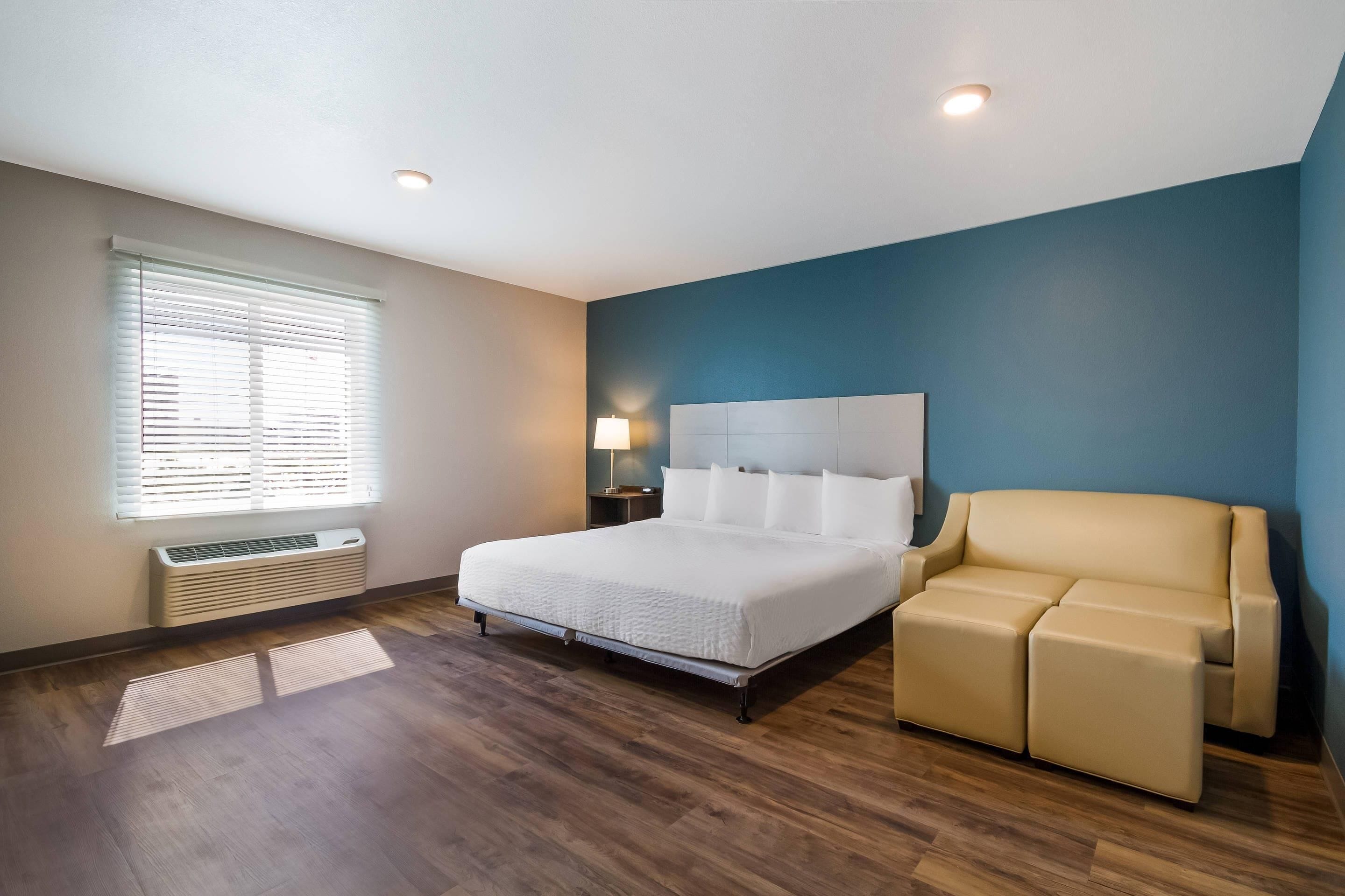 A bedroom with a bed, a bedside table, a lamp, and a sofa.